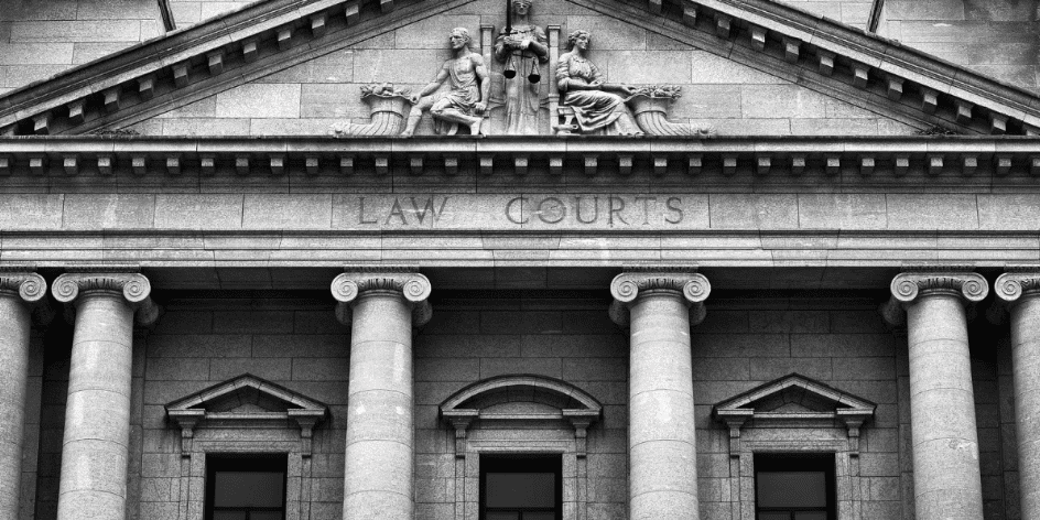 A courthouse with the words "LAW COURTS" engraved above the entrance. It features large columns and sculptures of figures holding a scale, symbolizing justice, above the door.